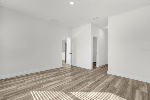 unfurnished room featuring light wood finished floors, visible vents, recessed lighting, and baseboards