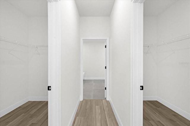 corridor featuring baseboards and wood finished floors