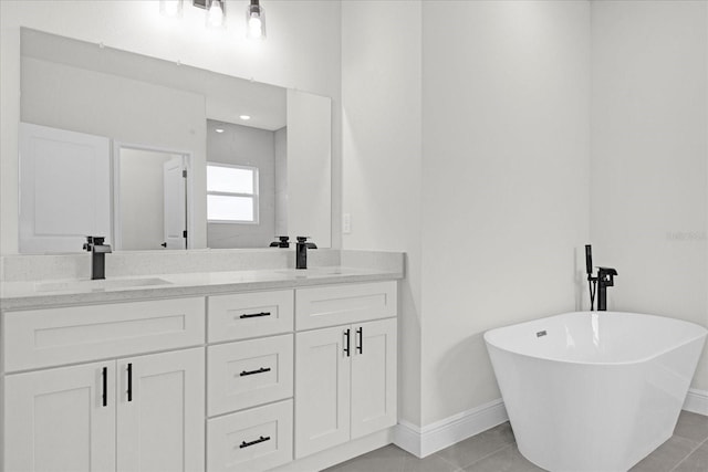 full bathroom featuring a freestanding bath, double vanity, baseboards, and a sink