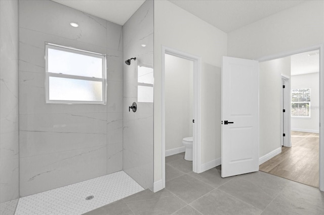 bathroom with a marble finish shower, toilet, and baseboards