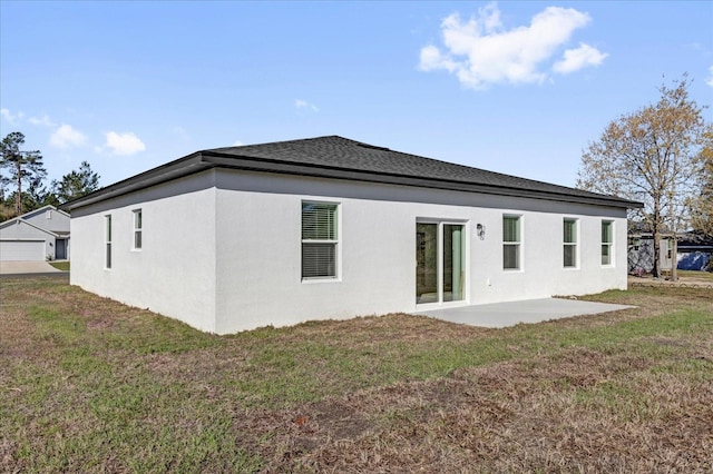 rear view of property with a patio, a yard, a garage, and stucco siding