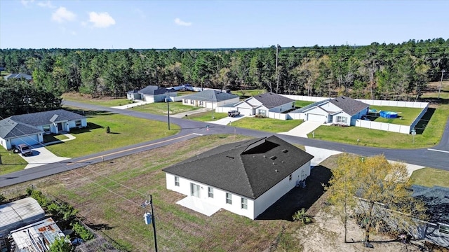 drone / aerial view featuring a wooded view and a residential view