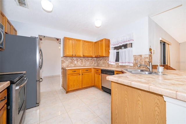 kitchen with visible vents, backsplash, a peninsula, stainless steel appliances, and a sink