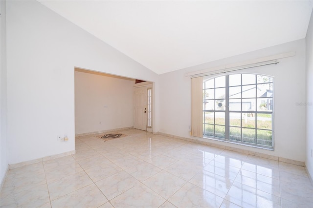 empty room with light tile patterned floors, baseboards, and high vaulted ceiling