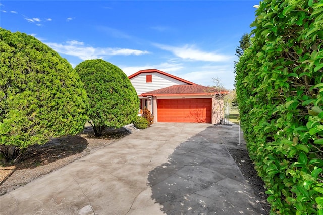 view of front of property featuring concrete driveway, a garage, and a shingled roof