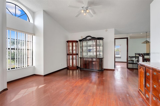 unfurnished dining area with vaulted ceiling, baseboards, a ceiling fan, and wood finished floors