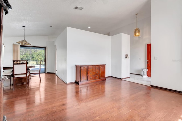 unfurnished living room with visible vents, baseboards, high vaulted ceiling, and wood finished floors