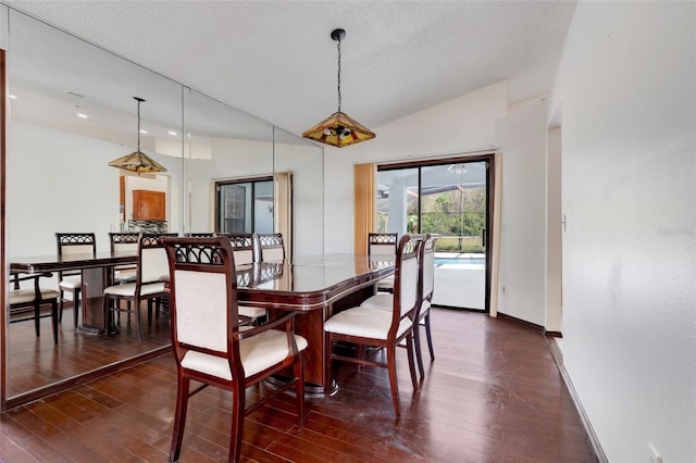 dining area with vaulted ceiling, baseboards, dark wood-style flooring, and a textured ceiling