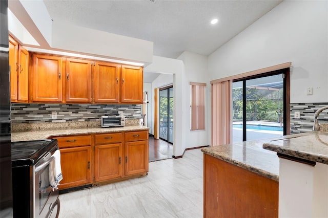 kitchen featuring light stone counters, brown cabinets, stainless steel electric range oven, and a wealth of natural light