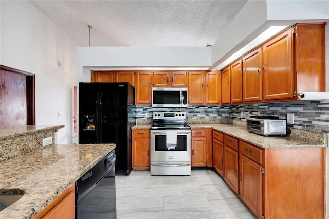 kitchen with a toaster, light stone counters, decorative backsplash, brown cabinetry, and black appliances