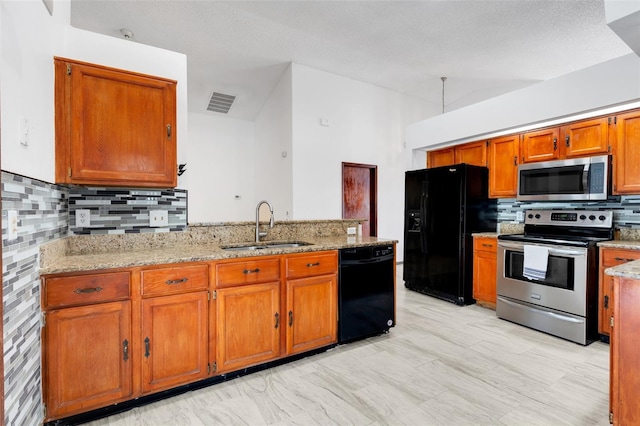 kitchen featuring visible vents, lofted ceiling, brown cabinets, black appliances, and a sink