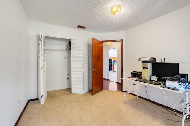 office area with light carpet, visible vents, and a textured ceiling