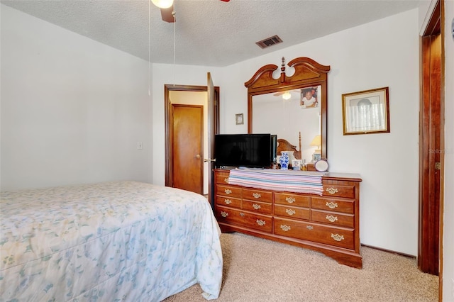 bedroom with visible vents, baseboards, light carpet, a textured ceiling, and a ceiling fan