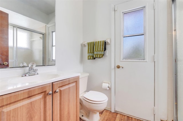 full bathroom featuring a shower with door, toilet, wood finished floors, and vanity