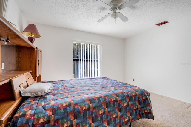 bedroom with a ceiling fan, visible vents, carpet floors, and a textured ceiling