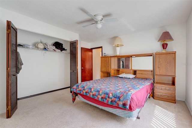 carpeted bedroom with a closet, baseboards, a textured ceiling, and a ceiling fan