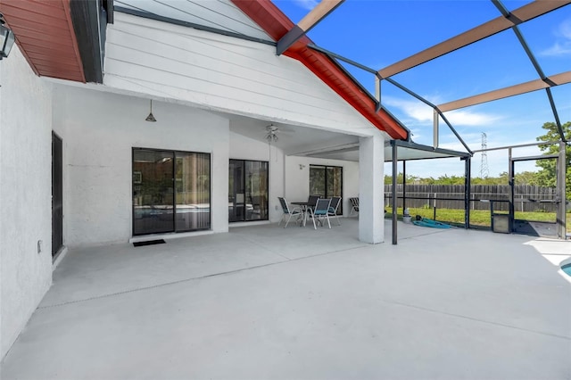 view of patio featuring glass enclosure, a ceiling fan, and fence