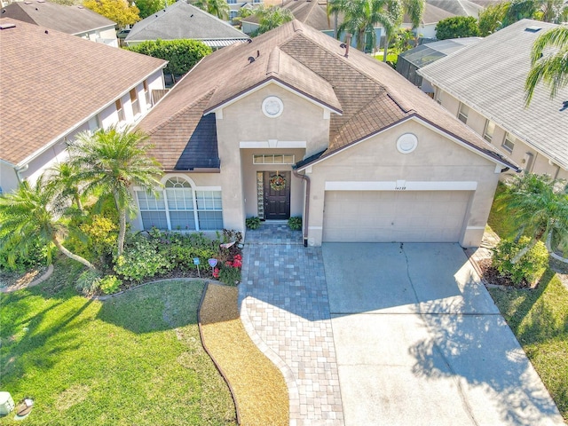 view of front facade featuring a front lawn, concrete driveway, roof with shingles, stucco siding, and an attached garage