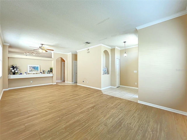 unfurnished living room with visible vents, arched walkways, light wood-style flooring, and a ceiling fan