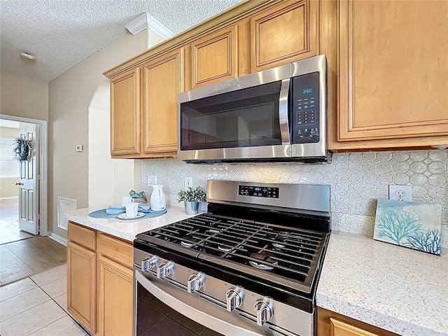 kitchen featuring visible vents, a textured ceiling, stainless steel appliances, light countertops, and decorative backsplash