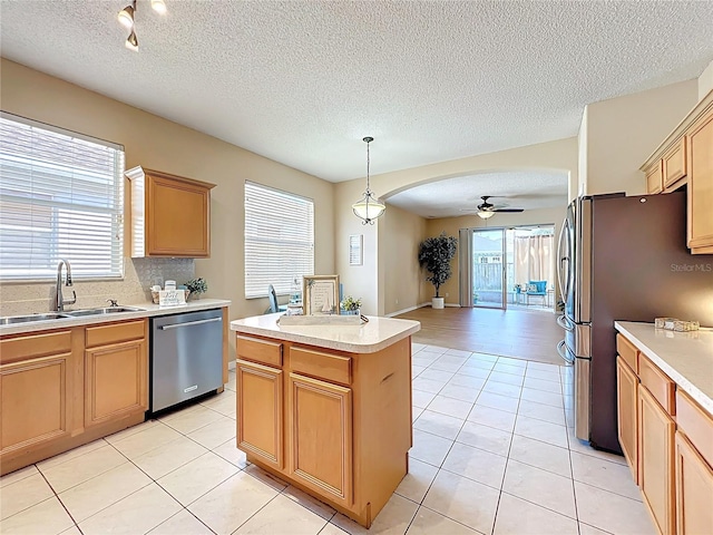 kitchen featuring a ceiling fan, a sink, a kitchen island, stainless steel appliances, and light tile patterned floors