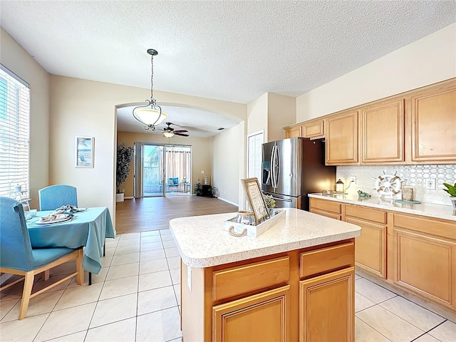 kitchen featuring light tile patterned flooring, a wealth of natural light, and stainless steel refrigerator with ice dispenser