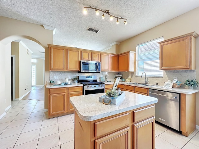 kitchen with visible vents, a sink, stainless steel appliances, arched walkways, and light tile patterned floors