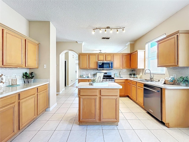 kitchen featuring visible vents, a sink, stainless steel appliances, arched walkways, and light tile patterned floors