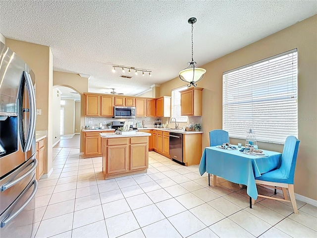 kitchen featuring a sink, backsplash, stainless steel appliances, arched walkways, and light countertops