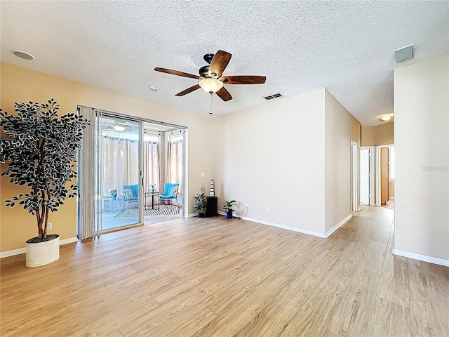 spare room with light wood finished floors, visible vents, baseboards, ceiling fan, and a textured ceiling