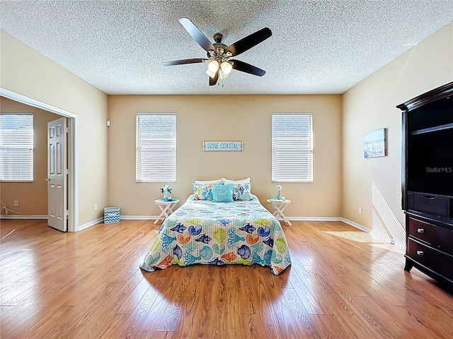 bedroom featuring light wood-type flooring, baseboards, a textured ceiling, and ceiling fan