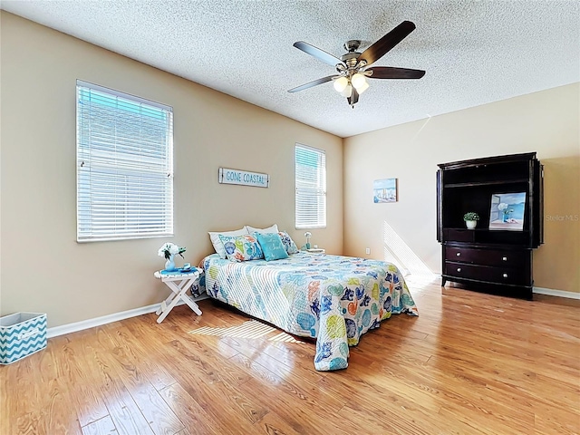 bedroom featuring baseboards, a textured ceiling, a ceiling fan, and hardwood / wood-style flooring