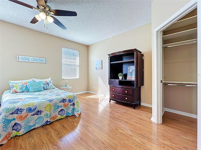 bedroom featuring light wood-style floors, baseboards, and a textured ceiling