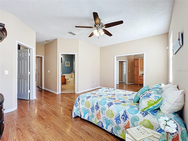 bedroom with visible vents, ensuite bathroom, a textured ceiling, light wood finished floors, and baseboards