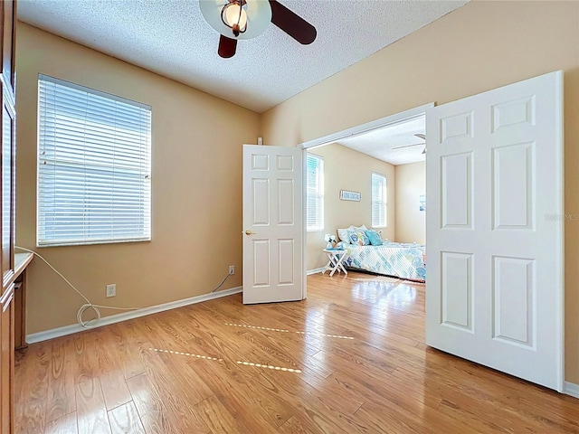 unfurnished bedroom featuring baseboards, a textured ceiling, ceiling fan, and light wood finished floors