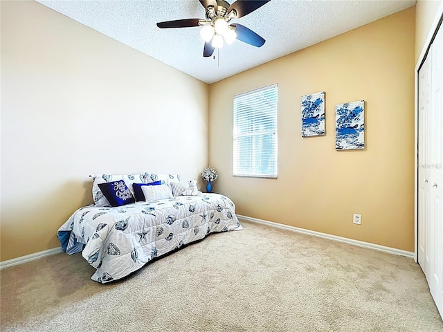 carpeted bedroom with a closet, baseboards, a textured ceiling, and ceiling fan