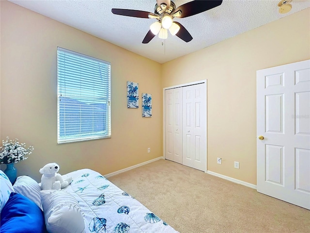 bedroom featuring light colored carpet, baseboards, a closet, and a textured ceiling