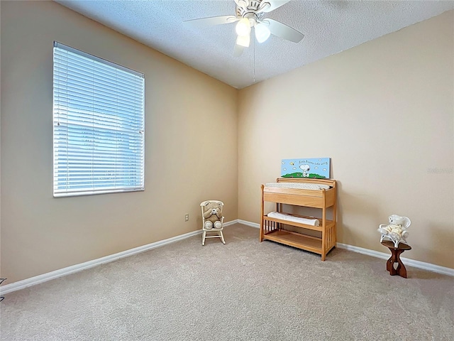 living area featuring a ceiling fan, baseboards, carpet floors, and a textured ceiling