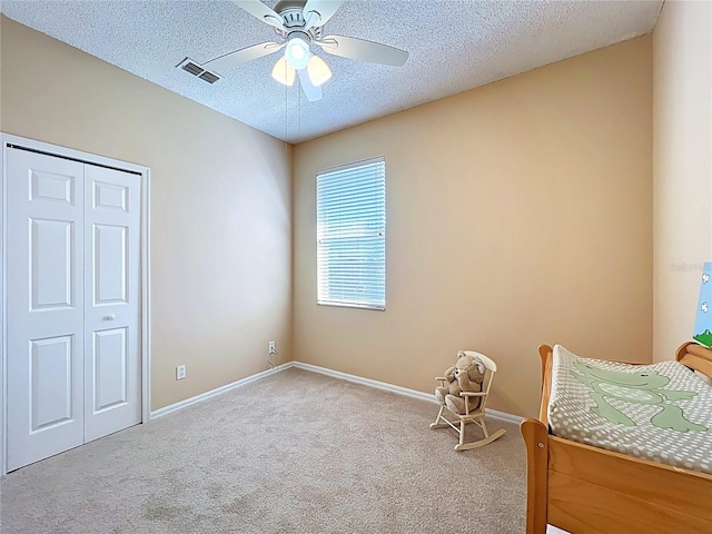 carpeted bedroom with visible vents, baseboards, a textured ceiling, and a closet