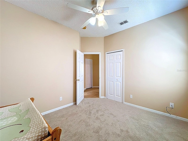 unfurnished bedroom with baseboards, ceiling fan, a closet, a textured ceiling, and carpet flooring