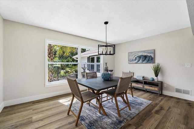 dining space featuring visible vents, baseboards, a chandelier, wood finished floors, and a textured ceiling