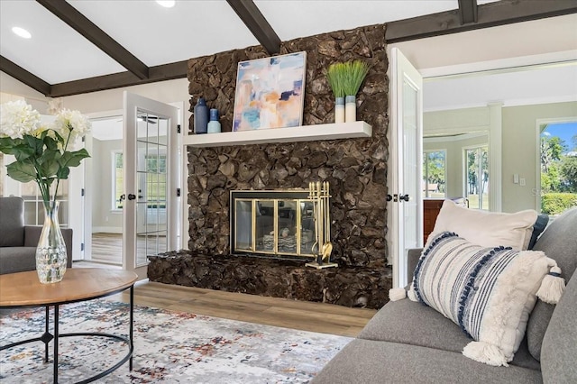 living room with plenty of natural light, a fireplace, vaulted ceiling with beams, and wood finished floors