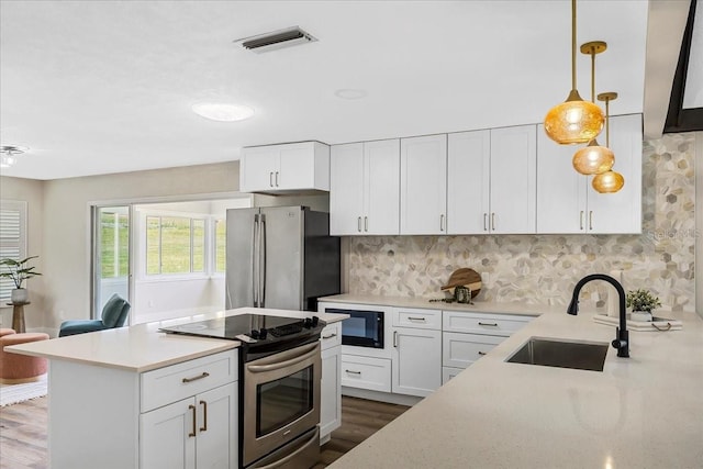 kitchen featuring tasteful backsplash, visible vents, white cabinets, stainless steel appliances, and a sink