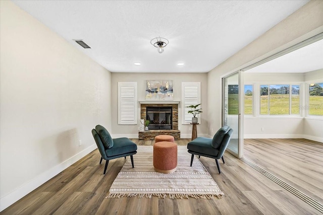 sitting room with visible vents, baseboards, wood finished floors, and a fireplace