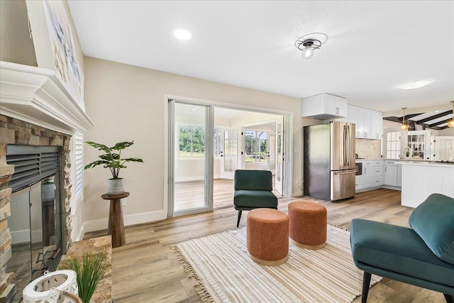 living area with light wood finished floors, recessed lighting, a fireplace, and baseboards