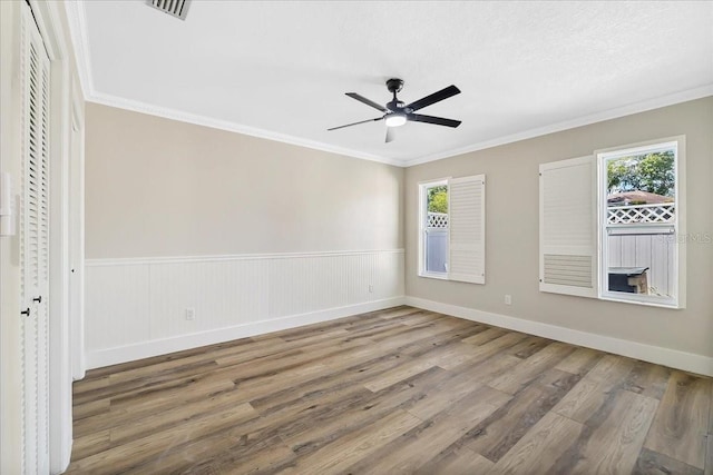 unfurnished room with crown molding, plenty of natural light, wood finished floors, and ceiling fan