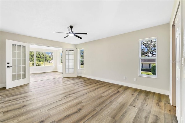 unfurnished room with ceiling fan, french doors, baseboards, and wood finished floors