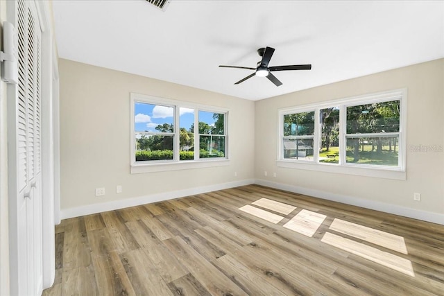 empty room with a healthy amount of sunlight, baseboards, a ceiling fan, and wood finished floors