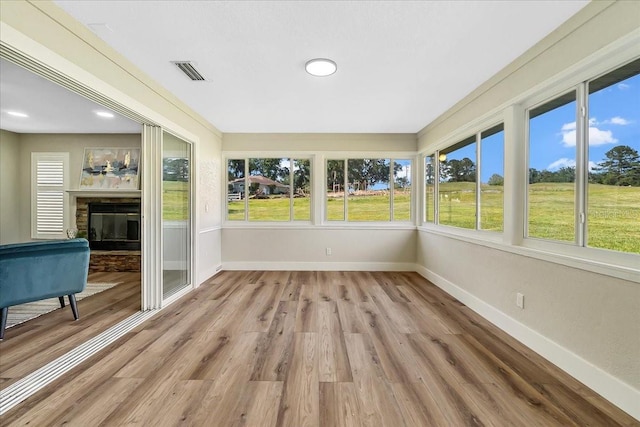 unfurnished sunroom featuring visible vents and a glass covered fireplace