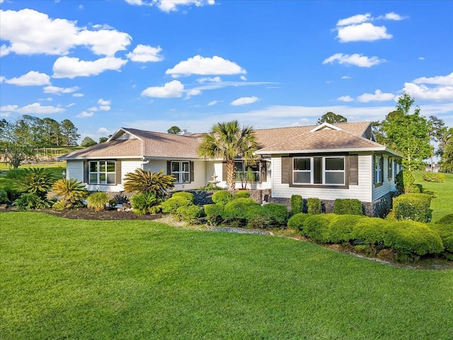 ranch-style home featuring stone siding, a front yard, and a shingled roof